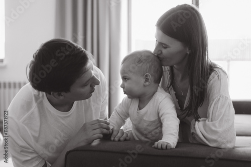 Loving parents kissing baby on forehead at home photo