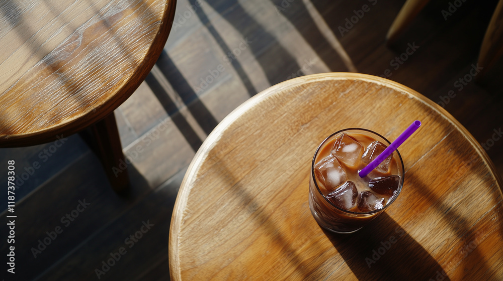 Cold coffee with ice cubes and a straw, placed on round wooden table, top view.
Cold coffee with ice cubes and a straw, placed on round wooden table, top view.