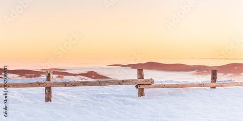 Fototapeta Naklejka Na Ścianę i Meble -  Eastern Sudetes, view of mountain range with thick fog in valley from peak from hiking trail during winter hike in mountains, viewpoint of wide winter landscape in mountains at orange sunset.