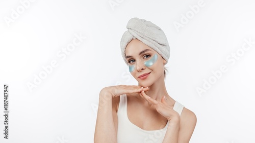 Wallpaper Mural 
Portrait of charming middle aged woman with towel on head applies beauty patches under eyes reduces wrinkles dark circles and fine lines wears minimal makeup poses against white background Torontodigital.ca