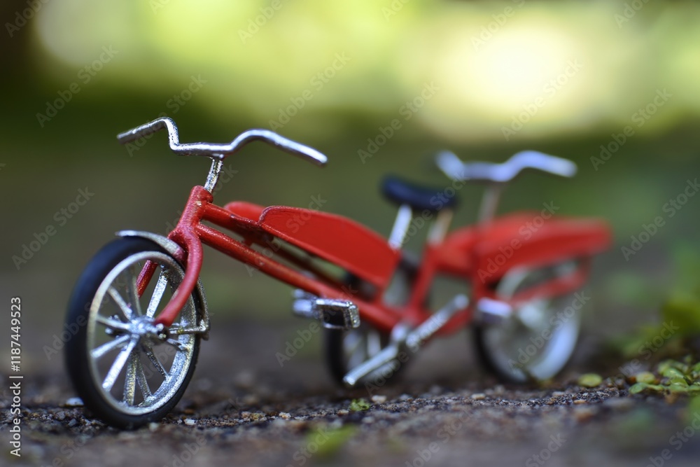 Obraz premium A small red toy bike sits on the ground, possibly waiting for its next adventure
