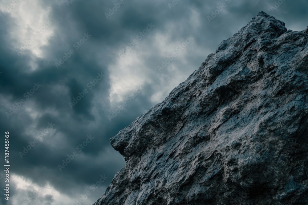 Fototapeta premium A rugged rock face with a cloudy sky in the background, suitable for outdoor or nature-inspired designs