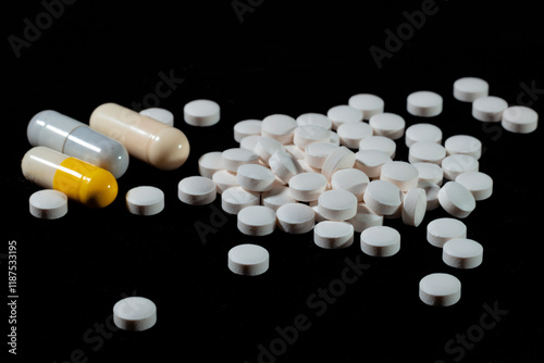 White round tablets are scattered on a black background.