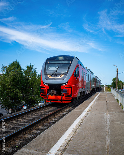 the approaching train to the pyrone against a background of blue sky, trees and cityscape.