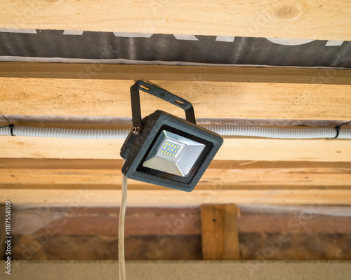 Temporary LED lantern suspended from the ceiling of a frame house under construction. renovation and construction