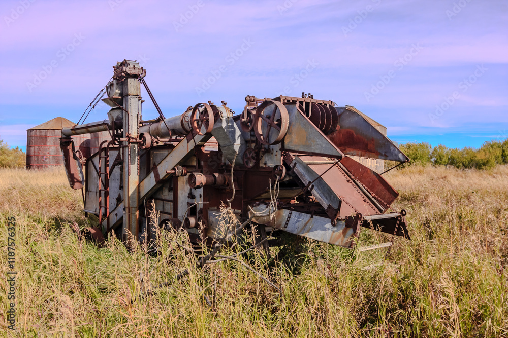Fototapeta premium An old, rusted combine harvester sits in a field
