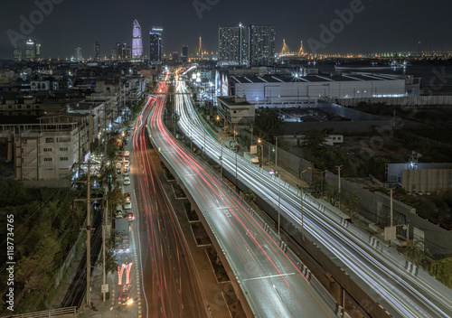 Nightscape view with bright glowing light trails of many cars on the road of Bangkok with Skyscrapers in the background. Long exposure for Light curve lines, use it as wallpaper, Poster and Space.
