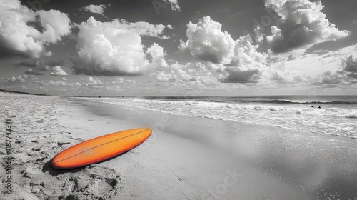 An Orange Surfboard on a Black and White Beach with Dramatic Clouds photo