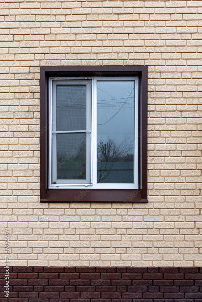 A window with a white frame and a brown sill sits in front of a brick wall A window with a white frame and a brown sill sits in front of a brick wall