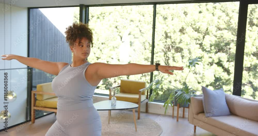 Practicing yoga, plus size woman stretching in warrior pose in living room Practicing yoga, plus size woman stretching in warrior pose in living room