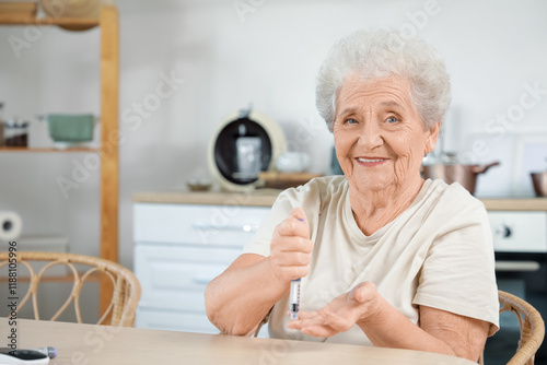 Diabetic senior woman using lancet pen at table in kitchen photo