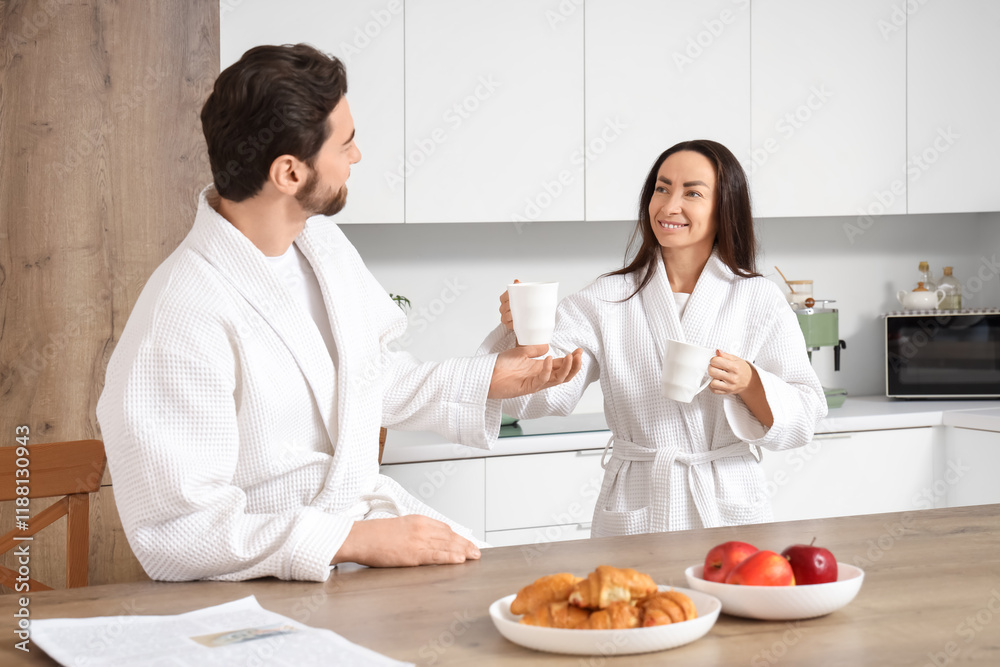 Beautiful woman giving cup of coffee to her husband in kitchen Beautiful woman giving cup of coffee to her husband in kitchen