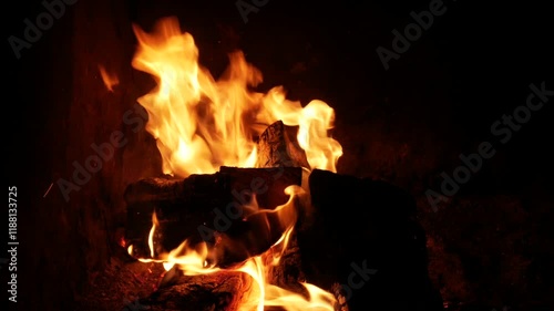 Burning wood in fireplace creating warm ambience on dark background
