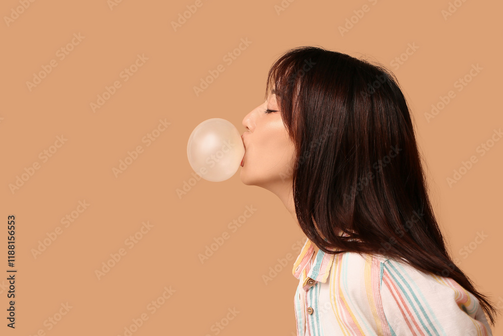 Pretty young Asian woman blowing bubble gum on beige background Pretty young Asian woman blowing bubble gum on beige background