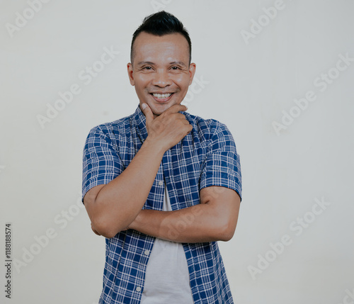 Asian man looking at camera with his hand on chin showing happy face, isolated on white background. photo