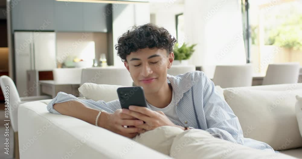 Relaxing on couch, teenage boy using smartphone and smiling at home Relaxing on couch, teenage boy using smartphone and smiling at home