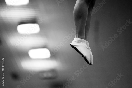 Male gymnast's feet in the air in right side of frame photo