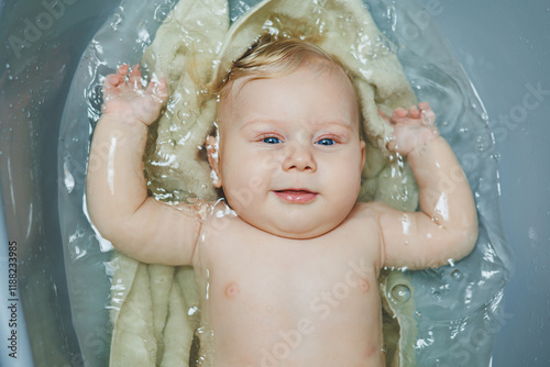 A small newborn boy of 5 months is bathing in a bathtub. Baby care. photo