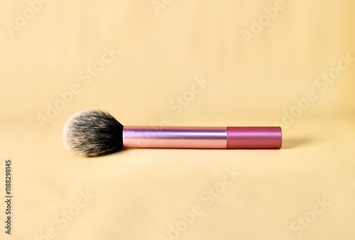 Blush make up brush with pink handle isolated on horizontal brown cream colored background. photo