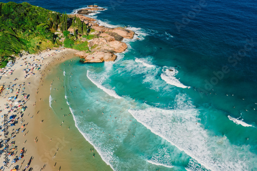 Aerial view of a beach with turquoise waters, surfers riding waves and colorful umbrellas in Brazil, Santa Catarina photo