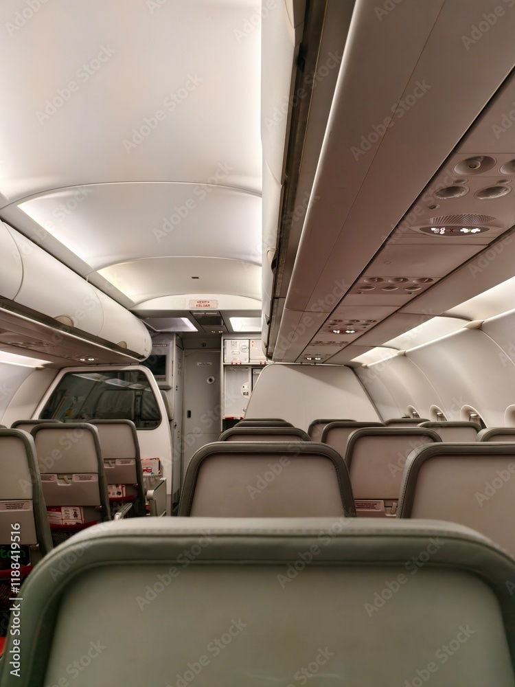 Obraz premium Airplane Cabin Interior with Passenger Seats, Overhead Compartments, and Cockpit View
