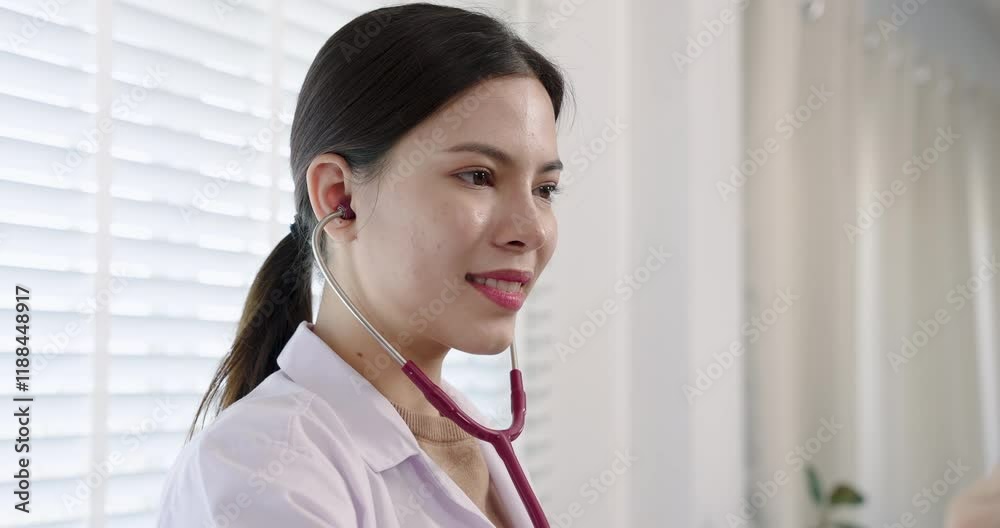 Smiling pediatrician using a red stethoscope in a bright hospital room. Clean setting with blinds filtering natural light, creating a calm and professional atmosphere for child patient care. Smiling pediatrician using a red stethoscope in a bright hospital room. Clean setting with blinds filtering natural light, creating a calm and professional atmosphere for child patient care.