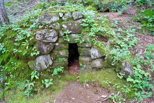 Entrance to a cave piled with stones in the mountains photo