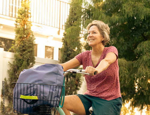 Close-up of a smiling woman cycling past a building, Florida, USA photo