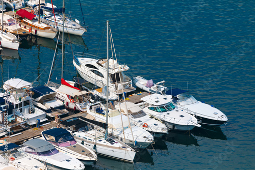 Obraz na płótnie Serene marina with several boats and yachts docked side by side. Variety of vessels, some with sails, others with motor engines, all moored in a calm water setting w salonie