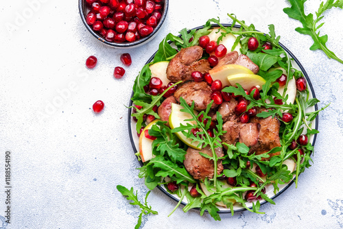 Salad rich in vitamins and minerals with chicken liver, apple, pomegranate and arugula. White background, top view photo