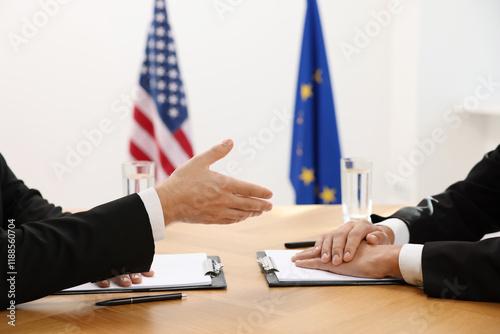 Diplomats negotiating during meeting at wooden table indoors, closeup photo