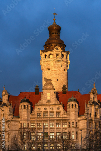Front view of the new town hall in Leipzig. The facade is illuminated by the low sun. Golden evening sun with a dramatically dark sky. Photo taken in winter.
