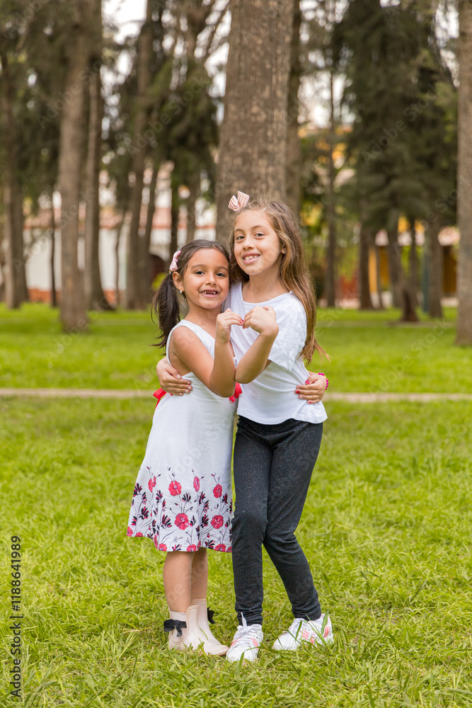 Two young girls are standing in a grassy field, hugging each other Two young girls are standing in a grassy field, hugging each other