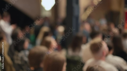 Soft-focused audience attentively observes tech presentation. Image hints at innovation reveal, technology conference. Related to tech startups, innovation showcases, tech event gatherings