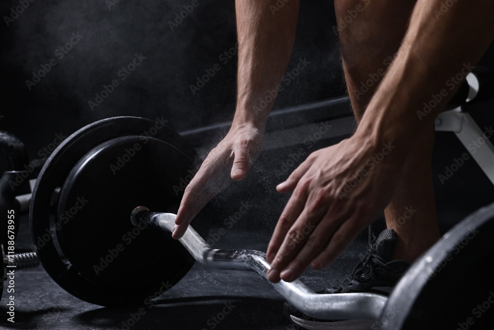Man clapping hands with talcum powder before training with barbell in gym, closeup Man clapping hands with talcum powder before training with barbell in gym, closeup