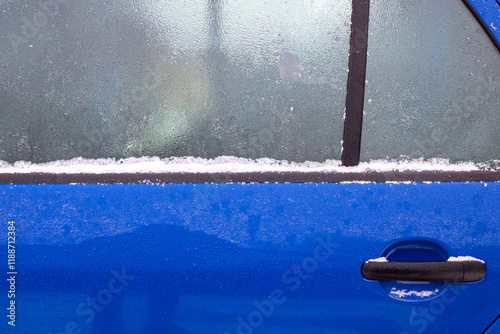 A sleek blue car is presently covered in a thick layer of snow and ice