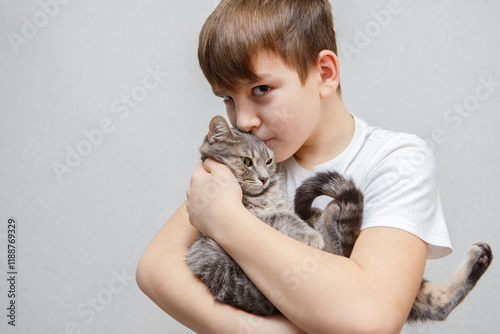 A cute ten year old boy tenderly holds a gray cat in his arms. photo