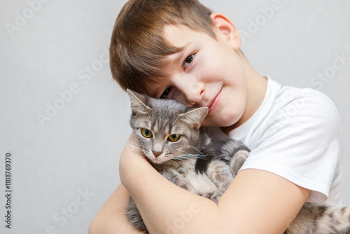 A cute ten year old boy tenderly holds a gray cat in his arms.