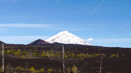 Mountains valley with black ground plains. Beautiful nature Autumn Winter landscape with snow-covered mountain peaks under clear blue sky in sunny weather