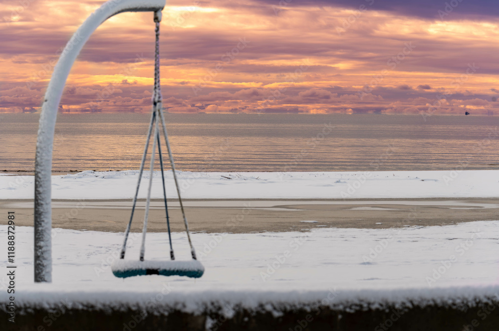 swing at the beach covered in snow frozen orange sky swing at the beach covered in snow frozen orange sky