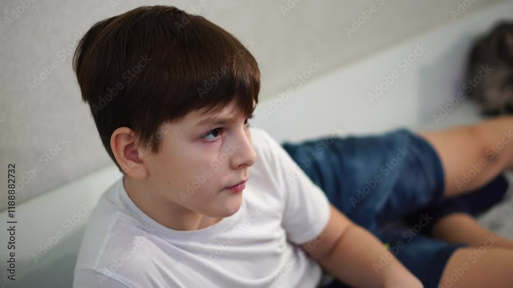 ten year old boy playing game console reclining on bed