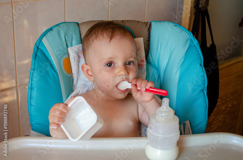 Nine-Month-Old Baby Eating Cottage Cheese in a High Chair photo