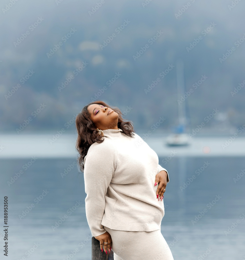 African female adult posing by lake on cloudy day African female adult posing by lake on cloudy day