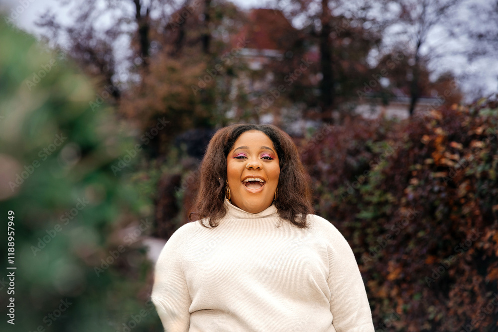 Smiling african female in autumn garden with bright makeup and cozy sweater Smiling african female in autumn garden with bright makeup and cozy sweater