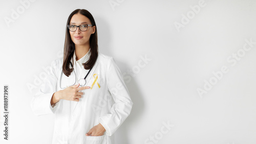 Childhood cancer awareness concept. Female doctor pointing at yellow ribbon on her lab coat, standing over white background, panorama, free space