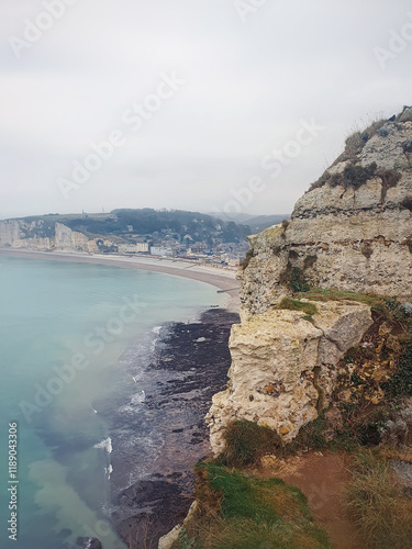 Coastal cliff with a view of Etretat town. Rocky hills and the calm sea scene photo