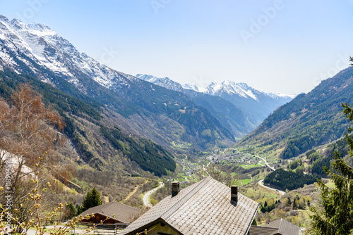 Green mountain valley overlooked by snow-capped peaks in the Swiss Alps on a sunny spring day photo