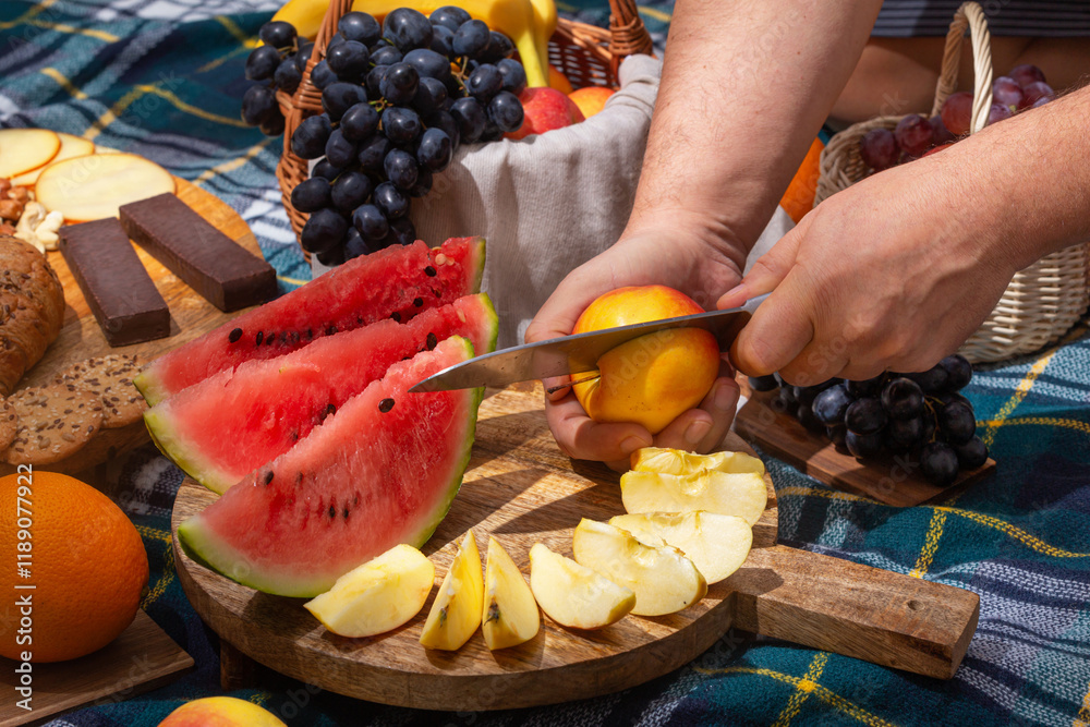 Close-up view of cut fruits against the background of laid out picnic food, selective focus. The concept of summer outdoor recreation on the weekend