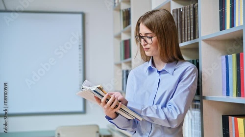 Portrait of student teenager girl holding textbooks inside classroom library