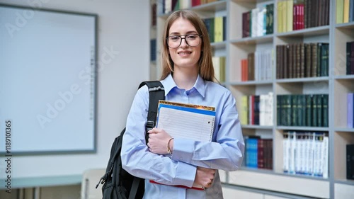 Portrait of student teenager girl holding textbooks inside classroom library